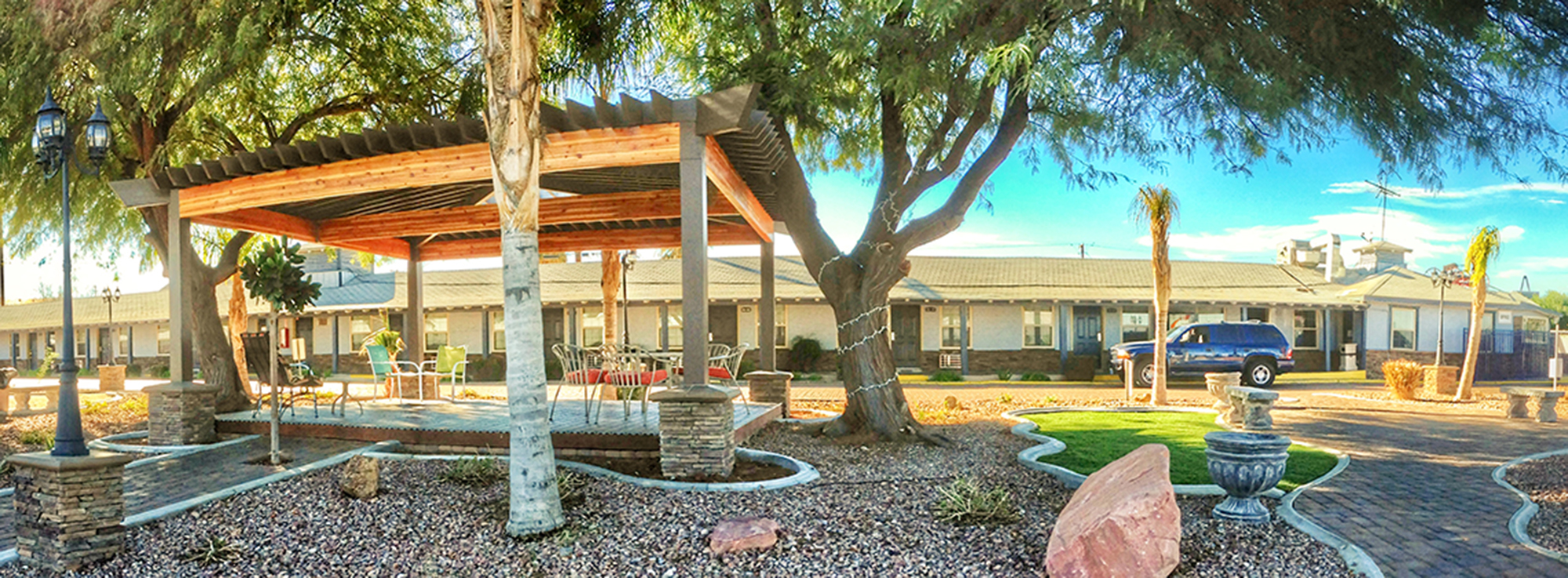 A tree surrounded by landscaping in front of a building with a patio area.