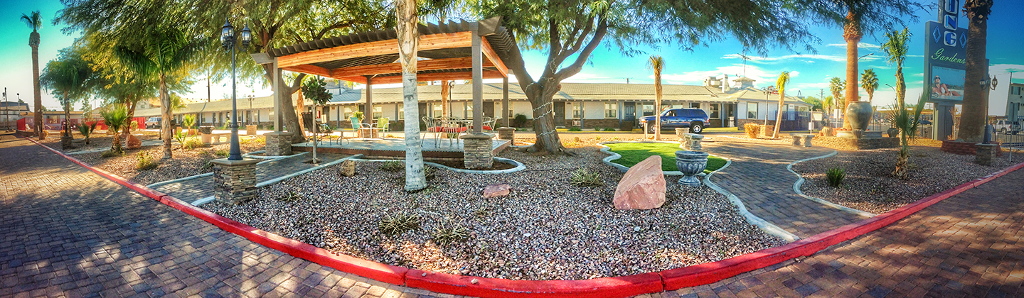 A landscaped outdoor area with a canopy, trees, and patio furniture.