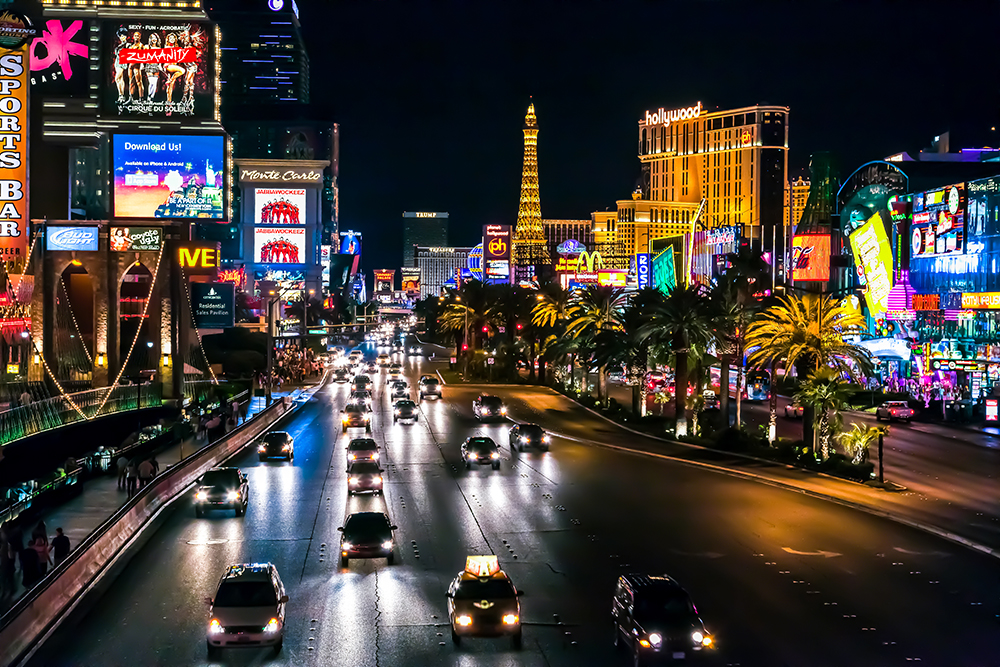 A nighttime view of a busy street with traffic and neon signs in a city.