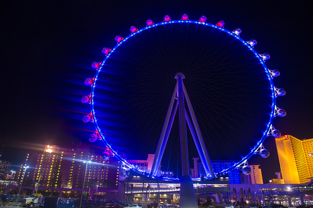 A large Ferris wheel is lit up at night in a city.